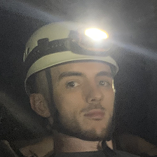 Headshot profile picture of Rhys Thomas wearing a head torch